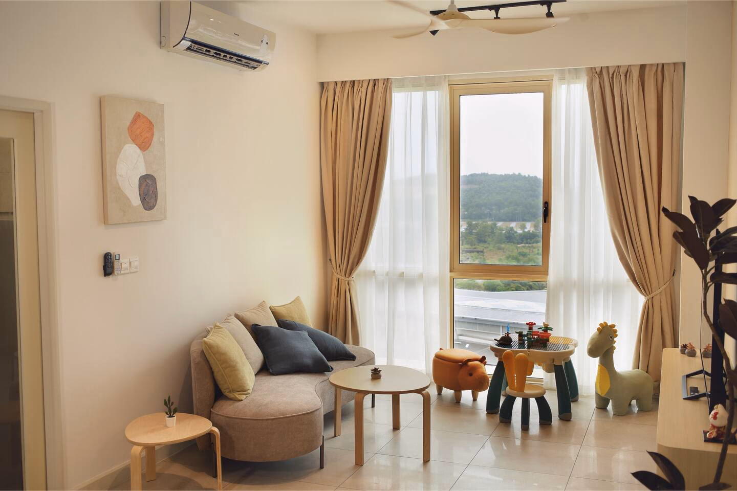 Living room of another RoomGuru-managed two-bedroom at Afiniti in Medini, with a children's play corner and a hillside view